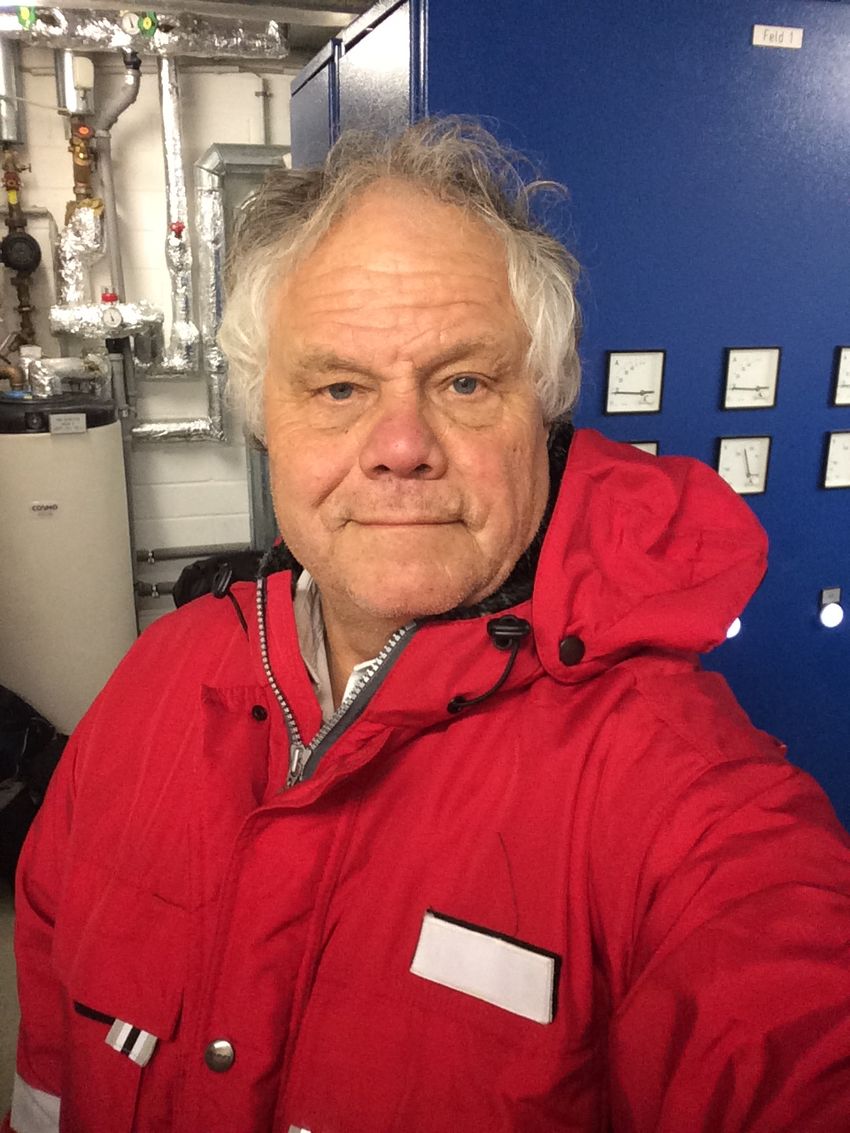 Giant virus expert Jean-Michel Claverie wears a red snow jacket in front of a blue wall.