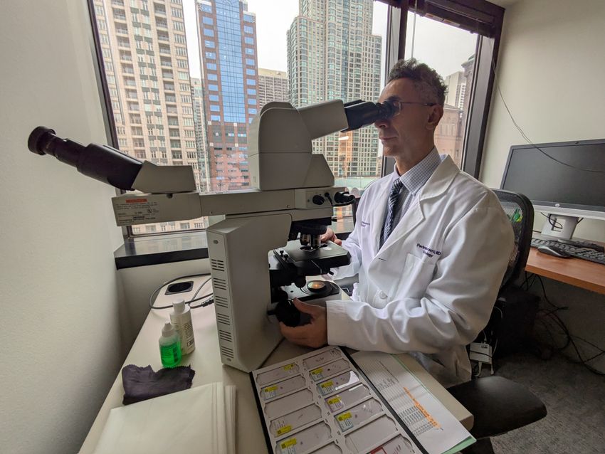Image of dermatologist and dermatopathologist Pedram Gerami looking at a skin biopsy in his office. Image of dermatologist and dermatopathologist Pedram Gerami looking at a skin biopsy in his office.