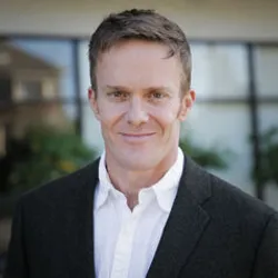 Jake Scott wears a dark suit jacket and a white button-down.