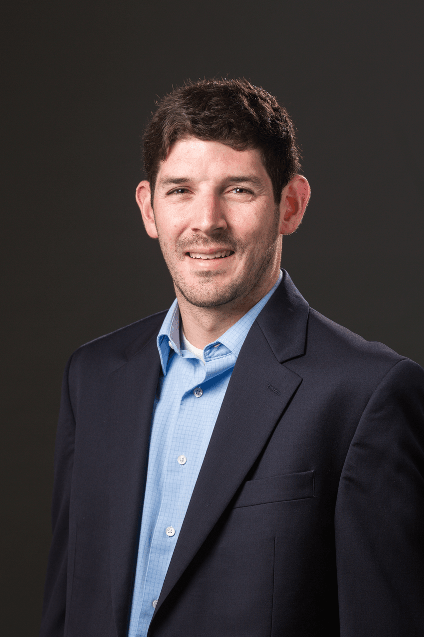 Professional photograph of Daniel Weinberger, an epidemiologist at Yale University, standing in front of a grey background. Weinberger has short dark hair and is wearing a navy suit jacket with a light blue collared shirt.