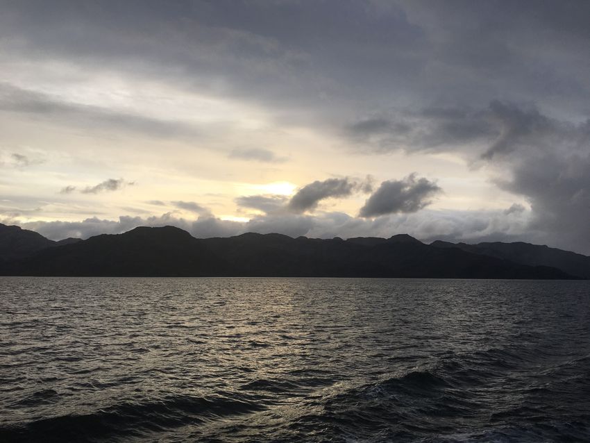 Punta Arenas is seen in a silhouette with the ocean in the foreground.