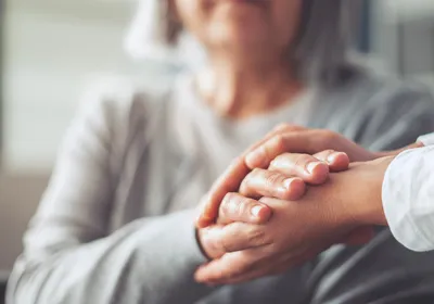 Hands holding an older woman’s hands.