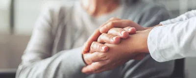 Hands holding an older woman’s hands.