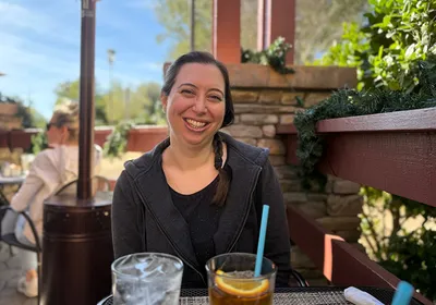 Image of Stephanie DeMarco smiling at the camera. She is in an outdoor seating area.