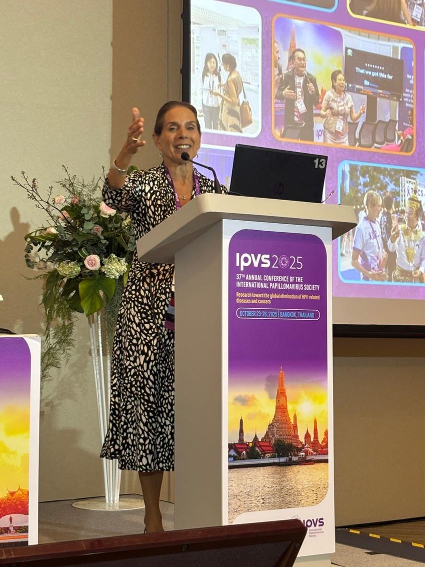 Anna Giuliano stands at a podium, giving a talk. She wears a black-and-white dress.
