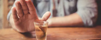 A man holds out his hand refusing an alcoholic drink.