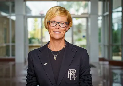 Image of bioengineer Nicole Steinmetz. She has short blonde hair, wears glasses, and is wearing a dark outfit as she smiles at the camera.