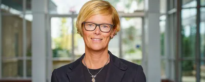 Image of bioengineer Nicole Steinmetz. She has short blonde hair, wears glasses, and is wearing a dark outfit as she smiles at the camera.