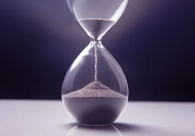 An hourglass stands upright with sand slowly flowing from the upper chamber to the lower one, indicating the accelerated aging in progeria.