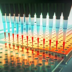 An automated multichannel pipette drops reagent into a multi-well plate