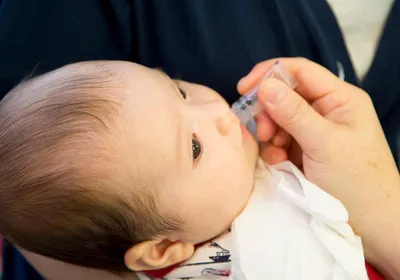 Infant receiving oral vaccination.