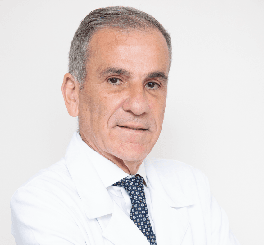 Photograph of Ricardo Cohen, a bariatric surgeon at the Hospital Alemão Oswaldo Cruz. Cohen has short, grey hair and is wearing a white lab coat with a dark tie.
