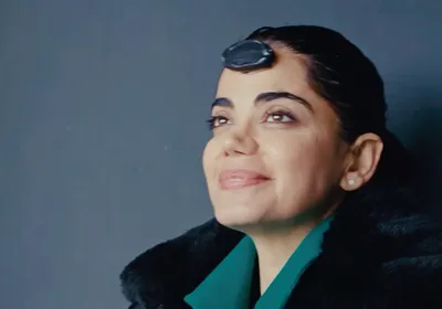 The photo shows Kiana Aran, after she just got out of her darkness retreat and opened her eyes, smiling. An EEG sensor is attached to her forehead.