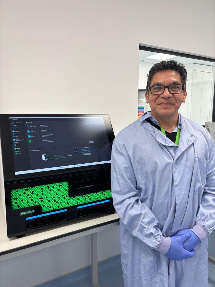 A scientist standing in front of a Bio-Rad ddPCR instrument in a laboratory. A scientist standing in front of a Bio-Rad ddPCR instrument in a laboratory.