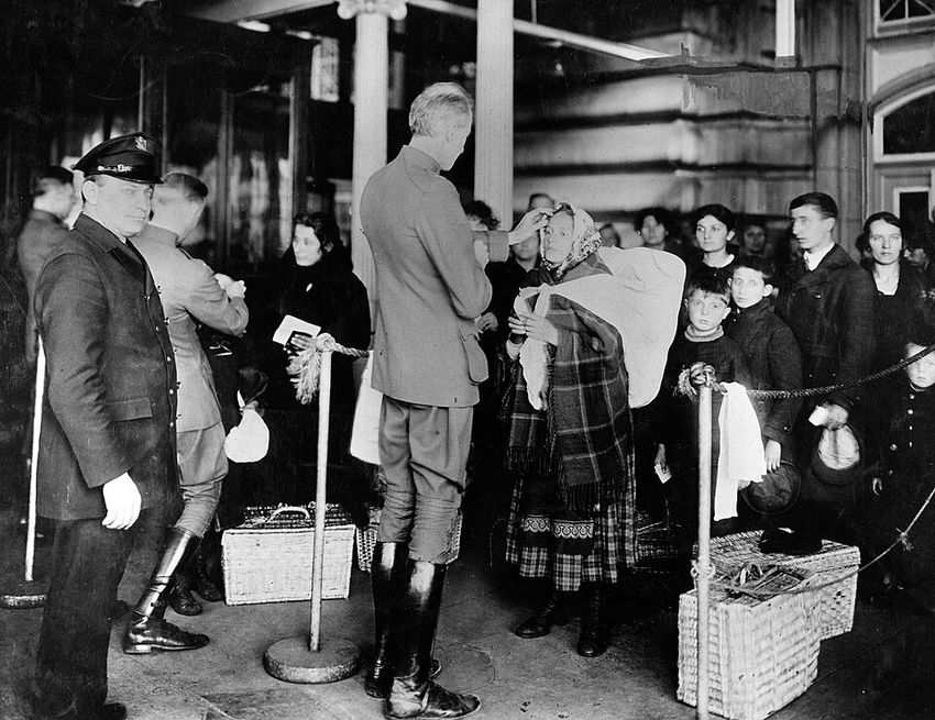 US immigrants stand waiting for their eyes to be inspected for a trachoma infection by physicians at Ellis Island.