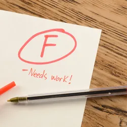 A graded school paper marked in red ink over a wood desktop.