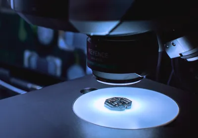Paradromics brain-computer interface implant undergoes device inspection by a large machine in a room lit in white and blue light.