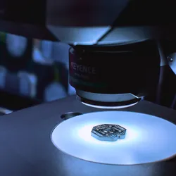 Paradromics brain-computer interface implant undergoes device inspection by a large machine in a room lit in white and blue light.