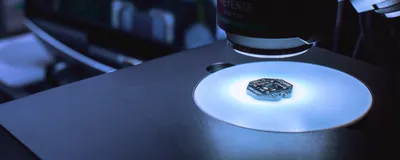 Paradromics brain-computer interface implant undergoes device inspection by a large machine in a room lit in white and blue light.