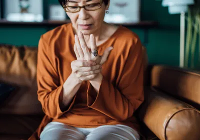 A woman holds her hand in pain. 