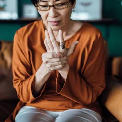 A woman holds her hand in pain. 