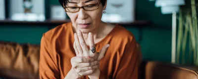 A woman holds her hand in pain. 