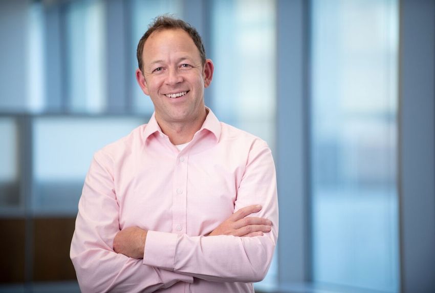 Josh Elias, who helped develop a new spatial proteomics method to map proteins’ subcellular localization, stands inside wearing a pink shirt with his arms crossed.