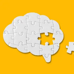 Photograph of a white puzzle in the shape of a brain on a yellow background. One puzzle piece from the center of the brain is missing. This photo represents a word losing its meaning in a phenomenon called semantic satiation.