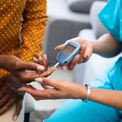 Young nurse doing a glucose blood test on her senior patient during a home visit.