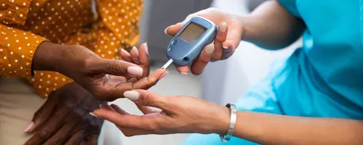 Young nurse doing a glucose blood test on her senior patient during a home visit.
