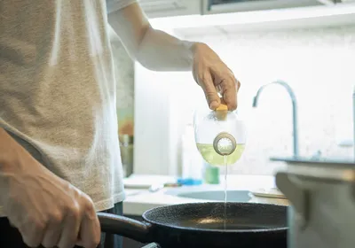 A middle-aged man cooks with non-stick cookware on a stovetop. 
