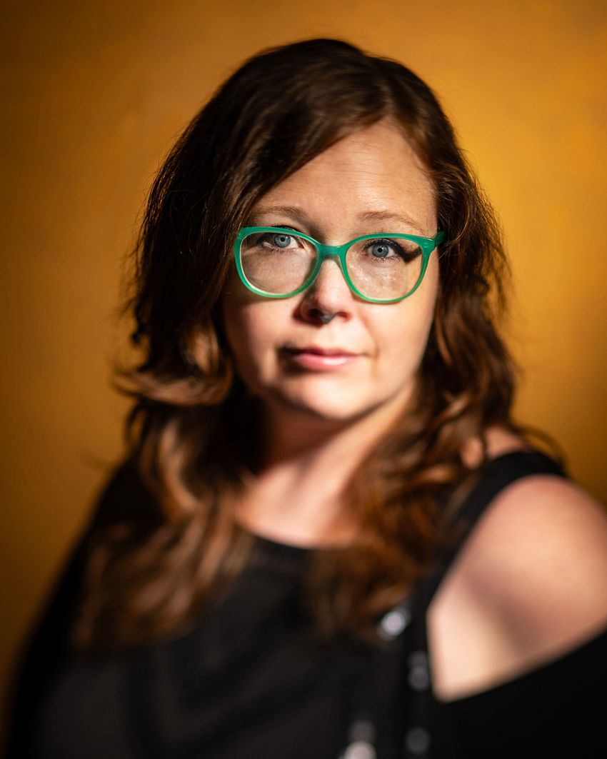 Image of artist and microscopy research fellow Jess Holz. She has long brown hair. She wears green glasses and looks at the camera.