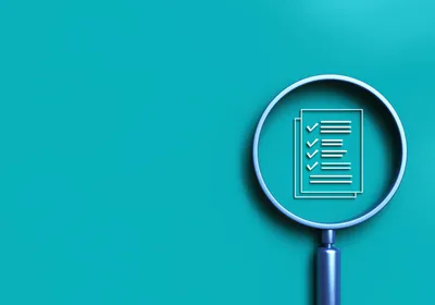 A magnifying glass over a regulatory compliance checklist icon