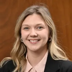Andrea Uhlig smiles in a headshot against a brown background.