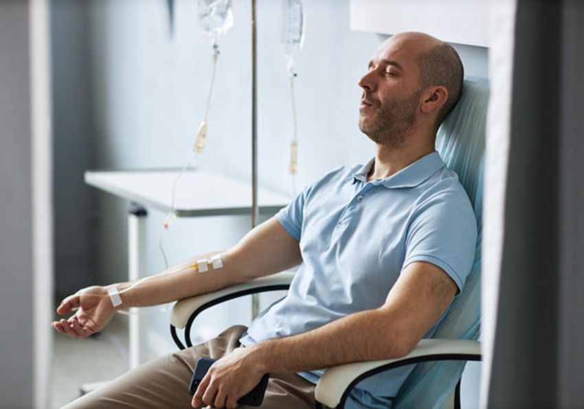 Photo of a male patient sitting on a chair in a clinic receiving intravenous cell therapy