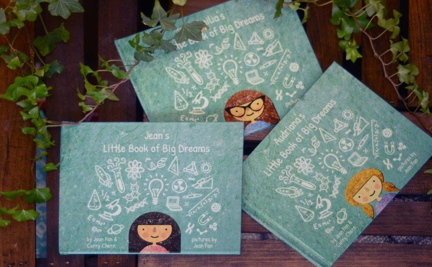 Three CuSTEMized books titled “Little Book of Big Dreams” containing different names placed on a wooden background with a few leaves.