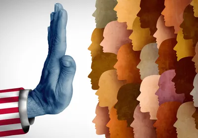Photo of an arm wearing an American flag sleeve holding a hand up against a crowd of skin-toned silhouettes, representing recent restrictions in hiring international research talent on H-1B visas.