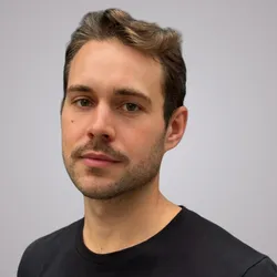 Alexander Morin wears a black shirt against a grey background in a headshot image.
