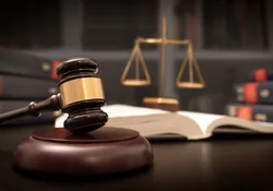 Image of judge gavel and scale against a background of books, signifying the court hearing arguments in the CRISPR patent battle.