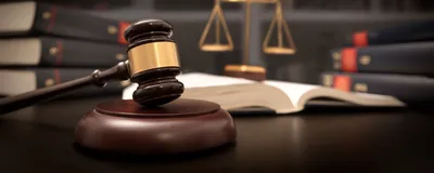 Image of judge gavel and scale against a background of books, signifying the court hearing arguments in the CRISPR patent battle.