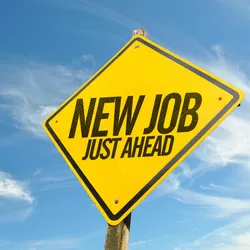 Photo of a bright yellow, diamond-shaped road sign with the words “New Job Just Ahead” printed in black. 