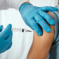 A doctor injects a teenager with a vaccine. 
