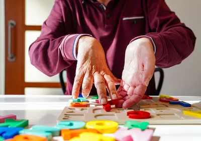 Image of a person with amyotrophic lateral sclerosis working with an alphabet puzzle for memory and coordination skills.