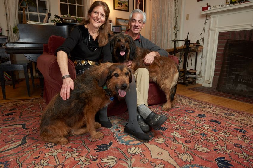 Jean Bennet and Albert Maguire sit in their living room with their two dogs.