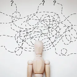 Cartoon of a wooden human-shaped figure against a white wall with several overlapping and tangled dotted lines above their head. The dashed lines end in question marks at the edge of the image. 