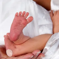 A newborn’s feet, with a band aid on the heel of one foot.