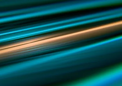 Abstract image of blue, green, and orange lines on a black background. 