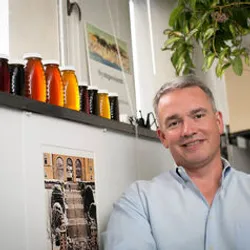 Phil Starks poses in his office near a row of vases and a hanging plant.