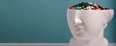 The lower half of a white ceramic head statue is filled with colorful pills to represent the placebo effect.