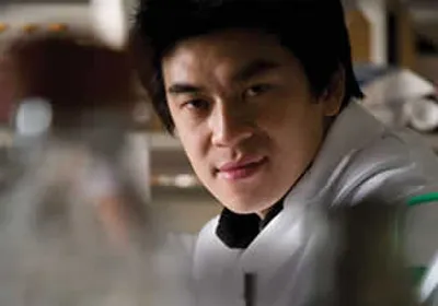 Howard Hang wears a white lab coat in a laboratory.